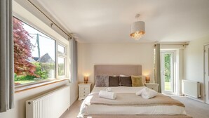 Ein Schlafzimmer mit einem großen Bett, Nachttischlampen, einer Heizung und Blick auf den Garten.