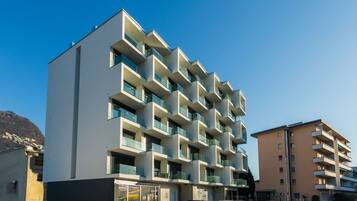 Ein mehrstöckiges Gebäude mit Balkonen, einem Parkplatz und blauem Himmel.