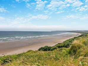 A coastal landscape with a beach, grassy areas, and a clear sky. - 2 Bed in Filey (oc-77711) (Hunmanby)