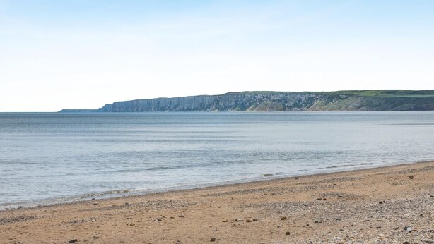 A beach with a rocky shoreline and cliffs in the background. - 1 Bed in Filey (oc-77709) (Hunmanby)
