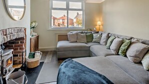 Ein gemütliches Wohnzimmer mit Kamin, einem großen Fenster mit Blick und einer Couch, sowie einer Hängeleuchte.