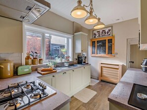 Eine Küche mit einem Gasherd, einem Fenster, einer Kreidetafel und einem Holzschrank.