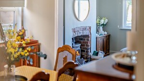 Ein gemütliches Zimmer mit Kamin, Esstisch und Spiegel.