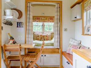 A cozy room with a wooden table, a bench, a window with curtains, and a bed with pillows. - 1 Bed in Aylesbury (oc-76403) (Ludgershall)