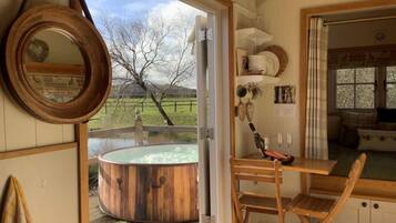 A room with a wooden hot tub, a wooden table, and a chair.