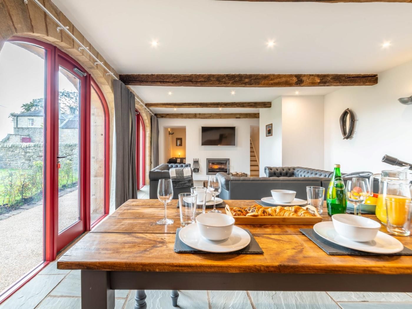 A dining area with a wooden table set for two, a fireplace, and a view of the outdoors.