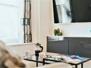 A living room with a coffee maker, two cups, a magazine, and a TV. - 1 Bed in Chester (oc-78221) (Chester)