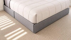 Un lit avec une tête de lit et un pied de lit gris, un matelas blanc et une couverture grise.
