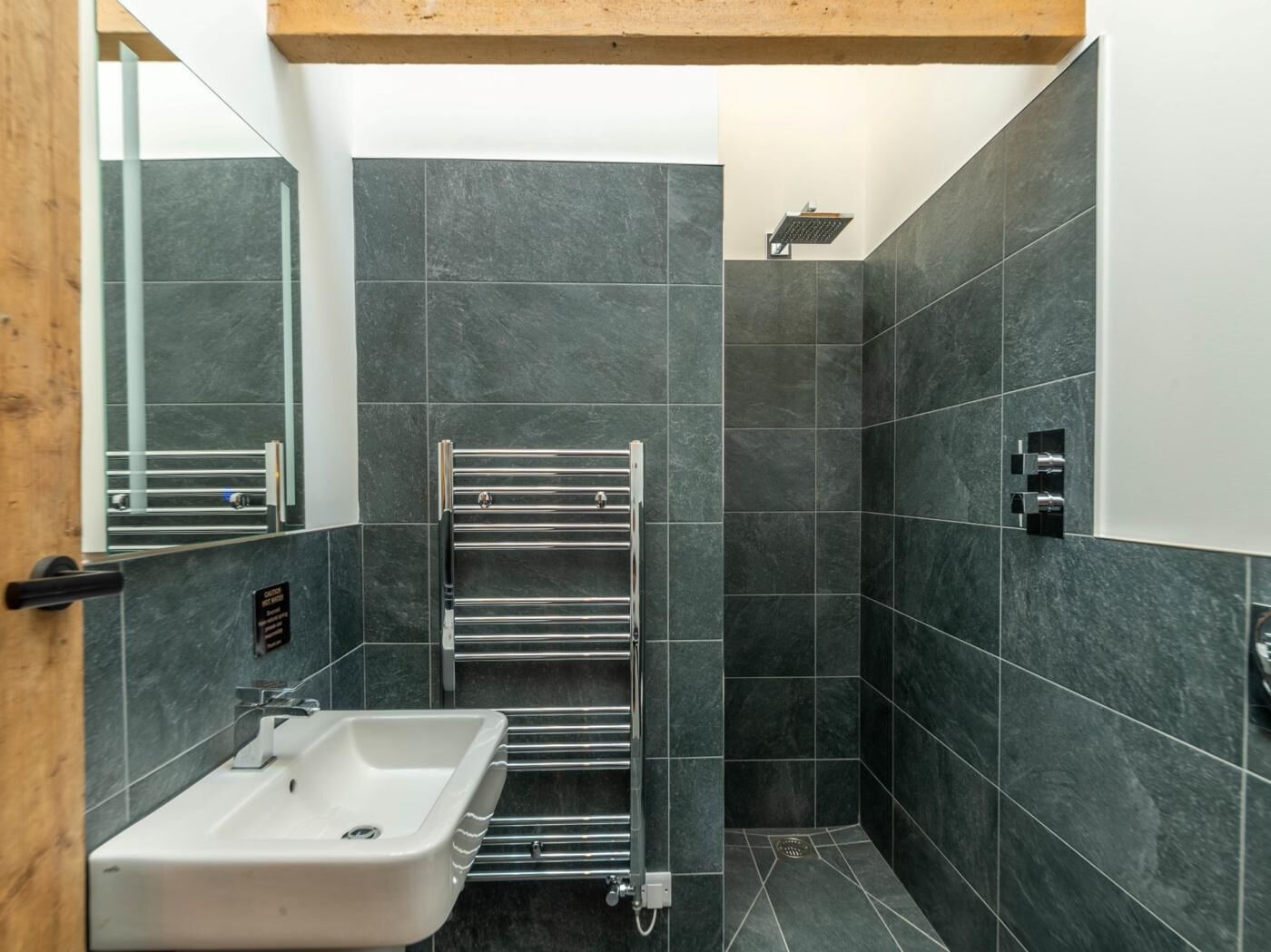 A modern bathroom with a white sink, a chrome towel rack, and a shower.