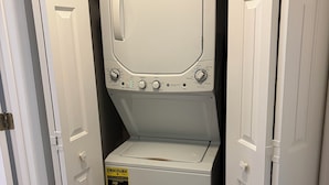 A front-loading washer and dryer unit with a ENERGY GUIDE sticker, located in a hallway with white doors. - Fairway Vista - Newly Renovated with Beautiful Golf Course views, 1bed-1 bath (Pawleys Island)