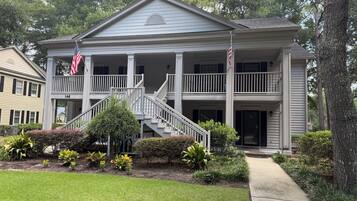 A two-story building with a central staircase, a covered porch, and a flag.