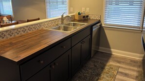 A kitchen with a wooden countertop, stainless steel sink, and dark cabinets. - Fairway Vista - Newly Renovated with Beautiful Golf Course views, 1bed-1 bath (Pawleys Island)