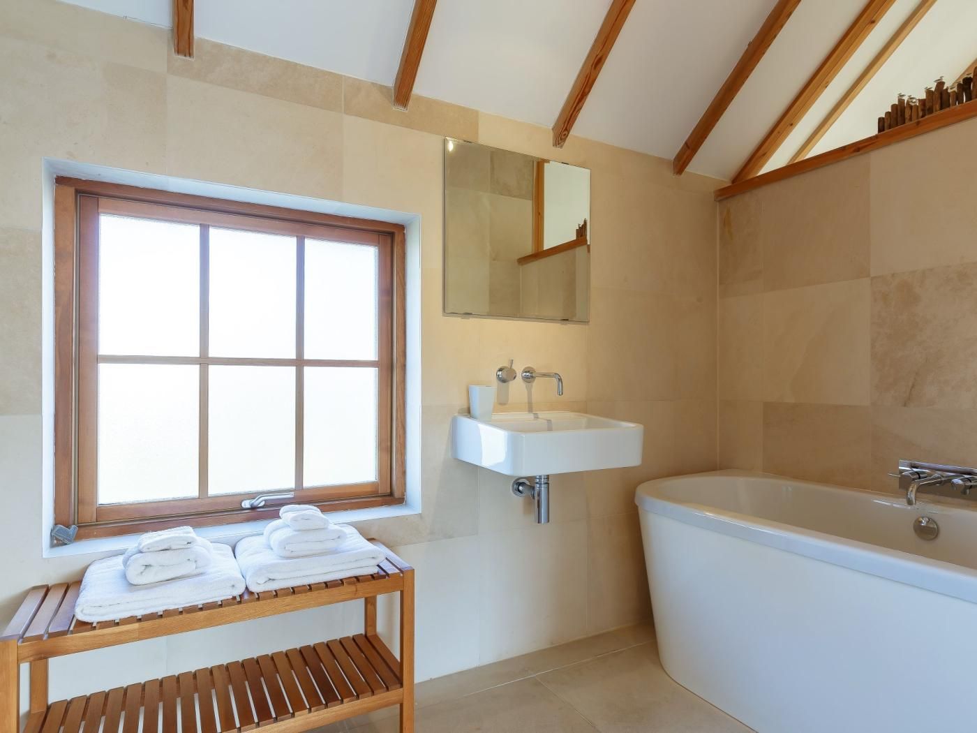 A modern bathroom with a window, a sink, a mirror, and a bathtub.