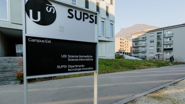 Un letrero que indica 'SUPSI Campus Est' con un edificio moderno al fondo.