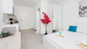 Una habitación de hotel moderna con una cama, un escritorio, una silla, un espejo y una planta en maceta.
