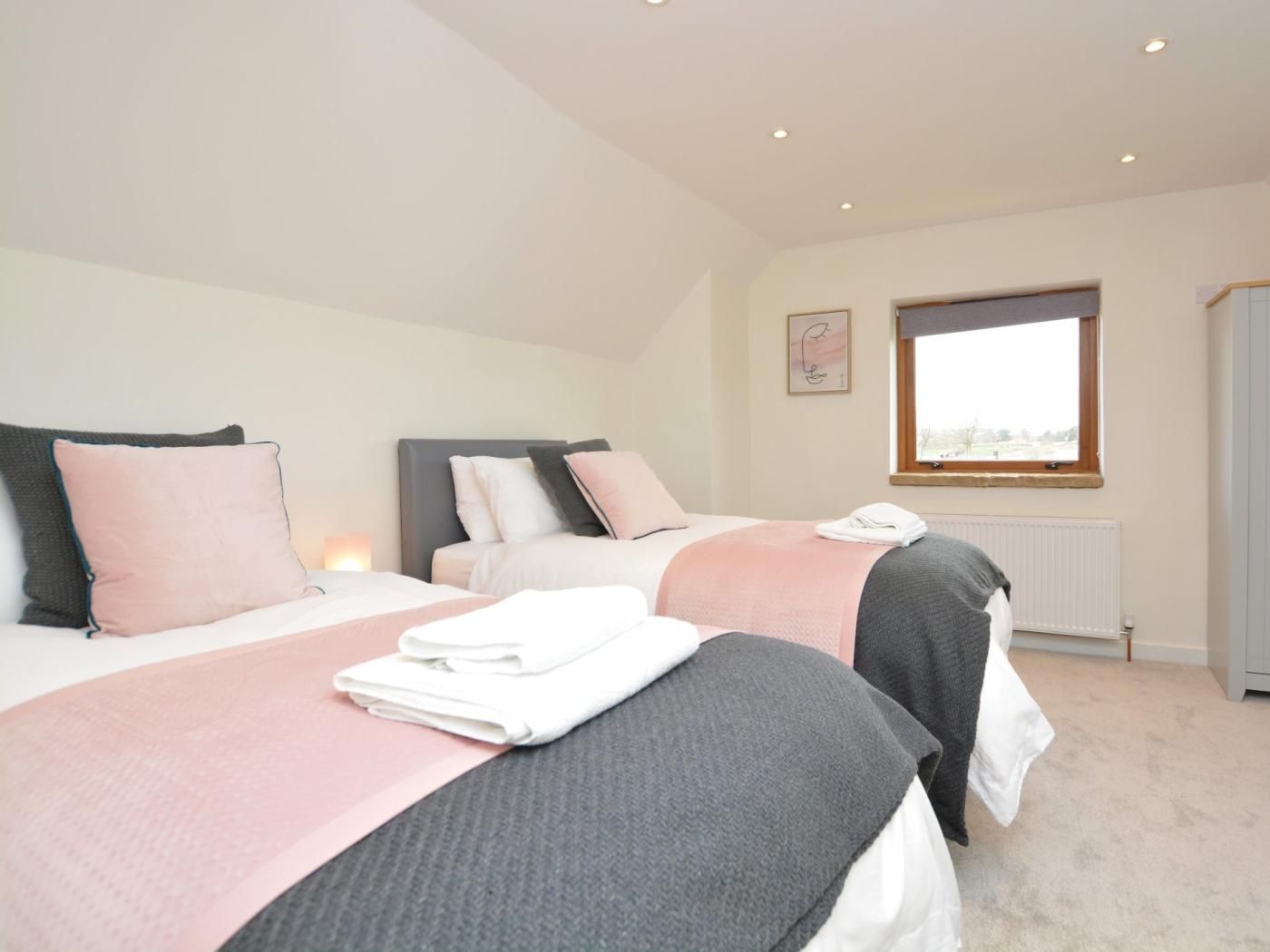 A bedroom with two beds, a window, and a radiator.