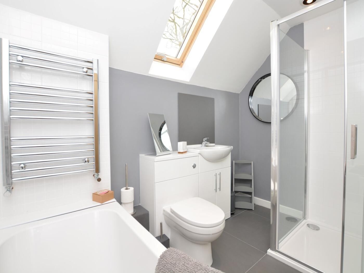 A modern bathroom with a skylight, a bathtub, a toilet, and a shower.