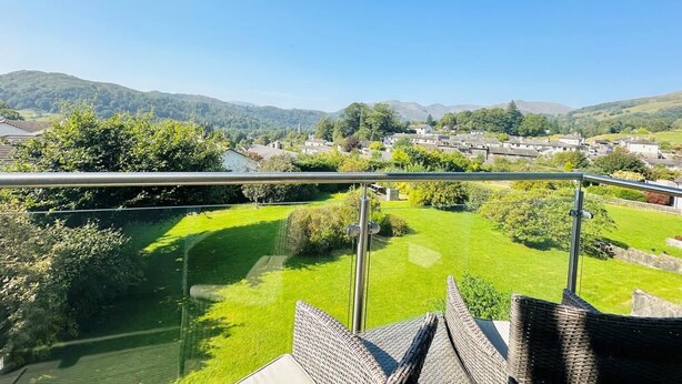 Varanda com vista desobstruída para uma paisagem verde e edifícios ao longe.