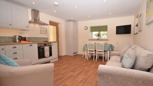Un espacio habitable compacto con kitchenette, comedor y una zona de estar con dos sofás.