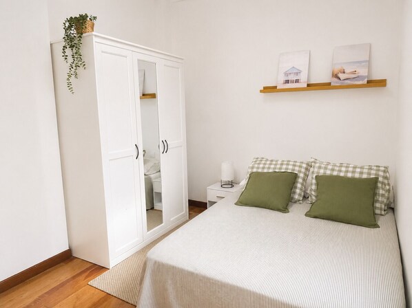 Une chambre à coucher comprenant un lit, une armoire, une table de chevet et une étagère murale décorée de tableaux.
