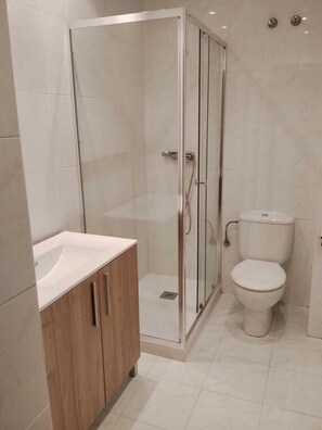 Une salle de bain moderne avec une douche à parois de verre, un lavabo blanc et des toilettes.
