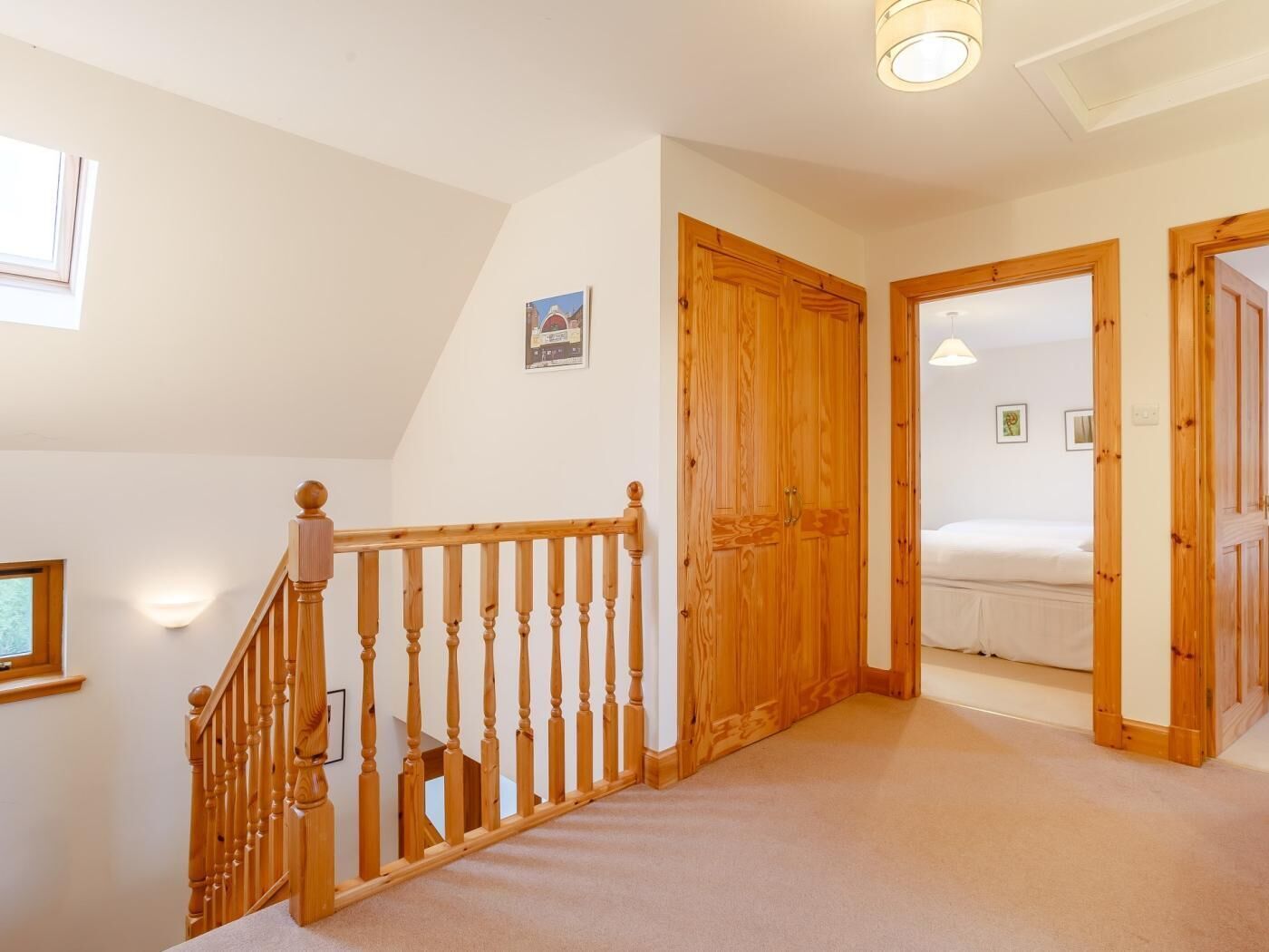 A staircase with wooden balusters leading to a bedroom with a bed and a nightstand.