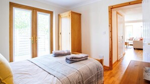 Un dormitorio con una cama, dos armarios de madera, una puerta de madera y vistas a otra habitación.