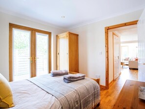 Ein Schlafzimmer mit einem Bett, zwei Holzschränken, einer Holztür und Blick in einen anderen Raum.