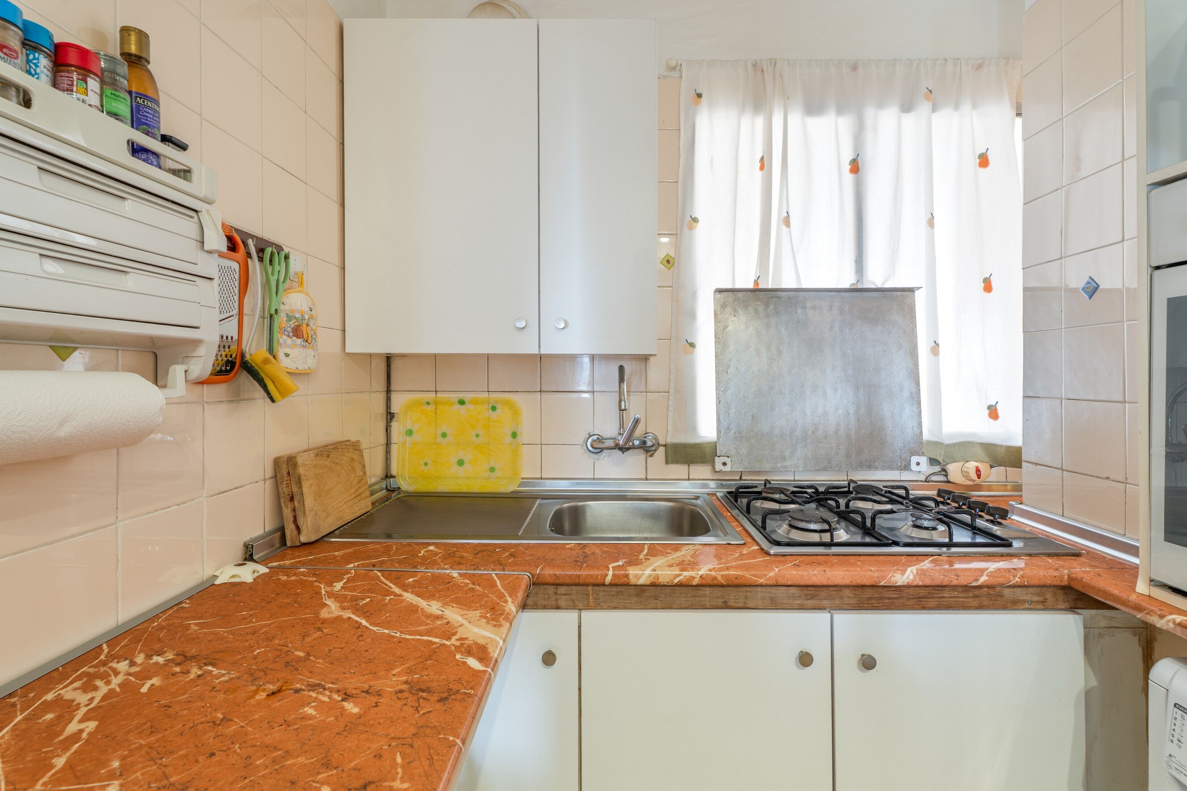 A kitchen with a gas stove, sink, and cabinets.