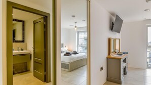 Ein Hotelzimmer mit Bad, einem Bett, einem Schreibtisch mit Computer und einem an der Wand befestigten Fernseher.