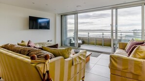 Ein modernes Wohnzimmer mit einem großen Schiebeglastür, die auf einen Balkon mit Meerblick führt.