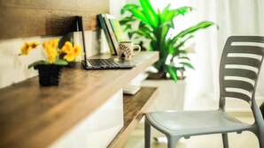 Een houten bureau met een laptop, een mok en een potplant.