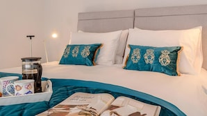 A neatly made bed with teal and white bedding, a coffee maker, and a tray with mugs on the side. - 1 Bed in Colwyn Bay (oc-78154) (Hen Golwyn)