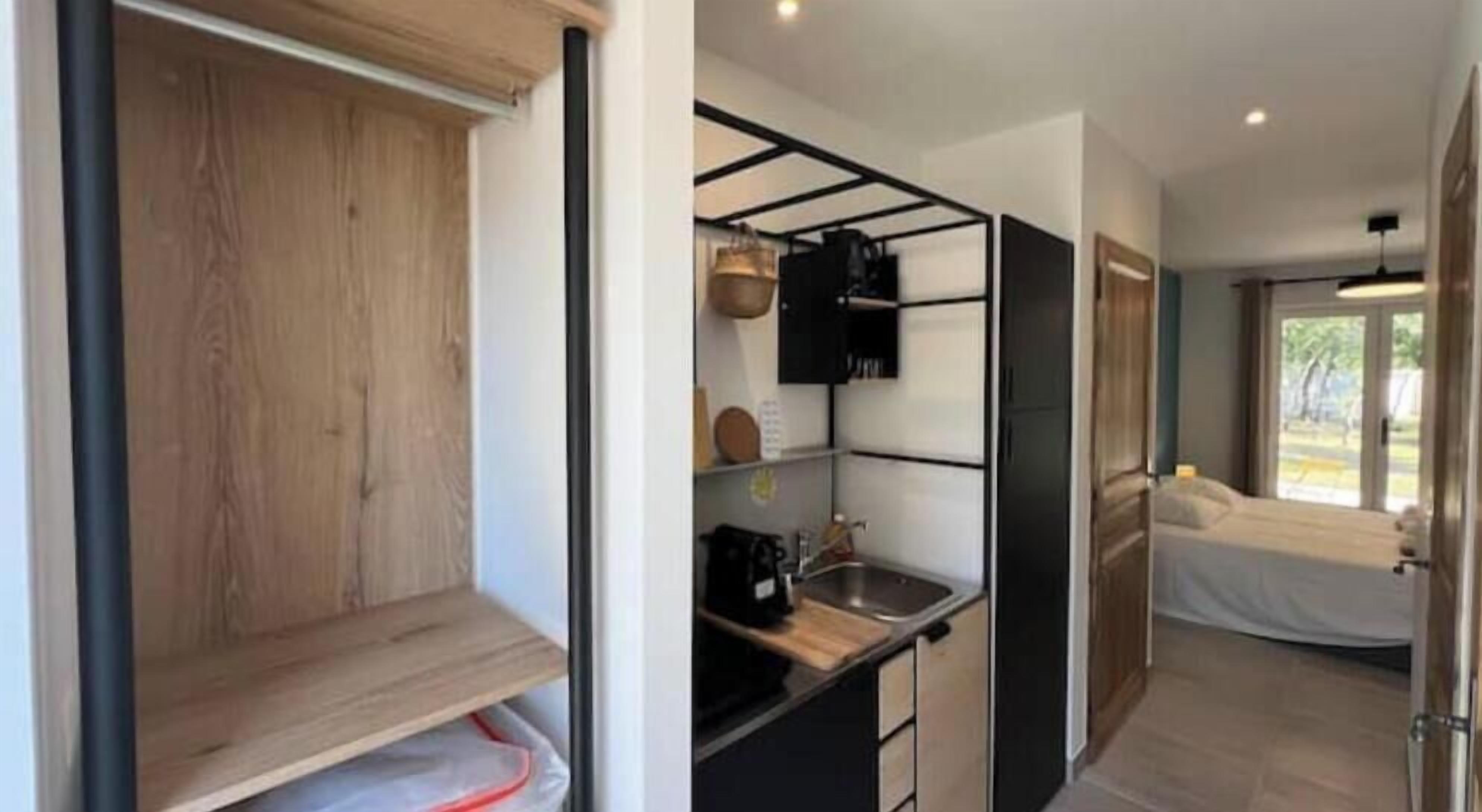A compact room with a kitchenette, a bed, and a view of the outdoors.