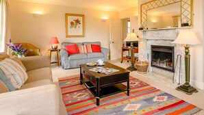 Una sala de estar con sofá, sillón, mesa de centro, chimenea y alfombra.