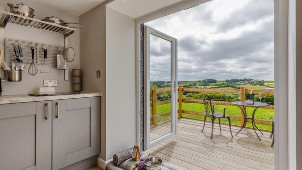 A modern kitchen with a large sliding glass door leading to a patio with a view of the countryside. - 1 Bed in Launceston (oc-78428) (Boyton)