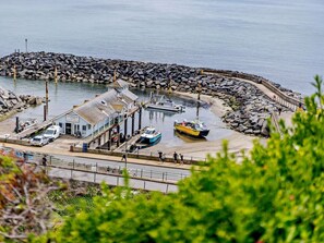 Ein Küstenort zum Fischfang mit einem Steg, Booten und einem kleinen Gebäude mit der Aufschrift 'Venture Bay Fishing'.
