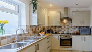 A modern kitchen with a stainless steel sink, a toaster, a microwave, and a stove. - 3 Bed in Ventnor (oc-80547) (Ventnor)