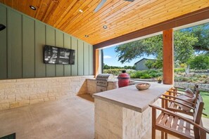 Ein Outdoor-Kochbereich mit Grill, einer Steinmauer und einer Holzbank.