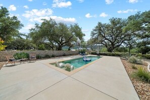 A backyard with a swimming pool, lounge chairs, and a stone wall. - Hill Country Retreat: Walk to Guadalupe River & (Canyon Lake)