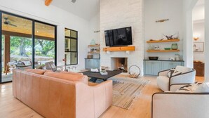 Una sala moderna con chimenea, televisor grande y sofá.