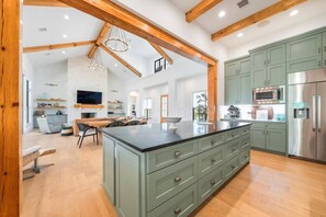 A spacious kitchen with a central island, built-in appliances, and a dining area with a modern chair and table. - Hill Country Retreat: Walk to Guadalupe River & (Canyon Lake)