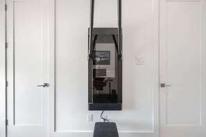 A room with a Pilates reformer machine mounted on the wall, a small bench, and a door with a handle. - Hill Country Retreat: Walk to Guadalupe River & (Canyon Lake)