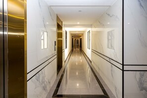 A long, narrow hallway with marble walls and a reflective floor, leading to a door at the end. - 1 Bedroom Apartment 15 Min to JKIA & SGR with Nairobi National Park Views (Nairobi)