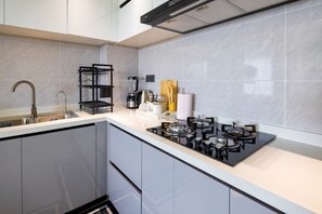 A modern kitchen with a gas stove, a coffee maker, and a sink. - 1 Bedroom Apartment 15 Min to JKIA & SGR with Nairobi National Park Views (Nairobi)