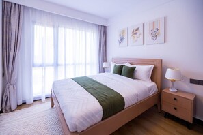 A neatly made bed with a green throw, a bedside lamp, and a nightstand. - 1 Bedroom Apartment 15 Min to JKIA & SGR with Nairobi National Park Views (Nairobi)