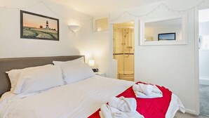 Et hotelværelse med seng, brusebad, et billede på væggen og et spejl.