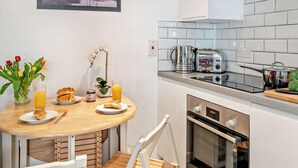Et moderne køkken med hvide fliser, en brødrister, elkedel og komfur.