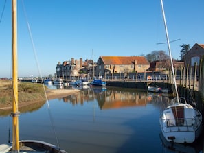 A calm harbor with boats, a stone building, and a clear sky. - 2 Bed in Holt (oc-78478) (Blakeney)