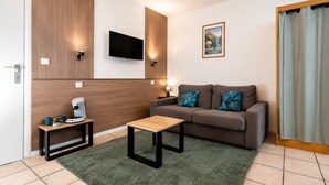 Una sala de estar moderna con un sofá, una mesa de centro, un televisor y un cartel en la pared.